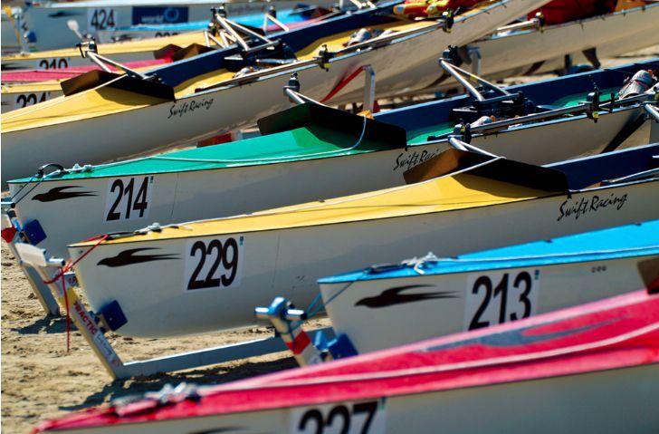 Multiple Swift coastal boats lined up on a beach showing custom boat numbers and names: 214, 229, 213, 424, 227